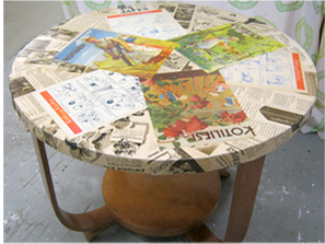 50-luvun pyöreä pöytä päällystettunä vanhoilla lehdillä ja lakattuna